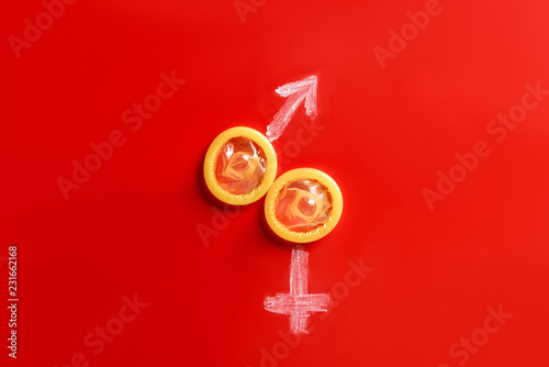 top view of condoms with male and female signs on red background