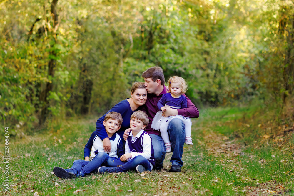 Portrait of young parents with three children. Mother, father, two kids brothers boys and little cute toddler sister girl having fun together in autumn forest. Happy family of five Portrait of young parents with three children. Mother, father, two kids brothers boys and little cute toddler sister girl having fun together in autumn forest. Happy family of five