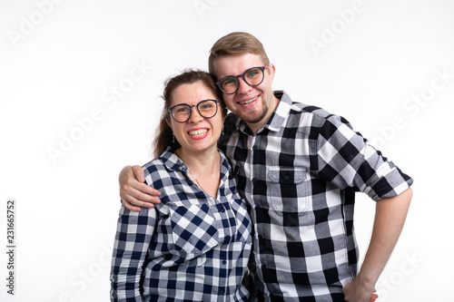 Nerds, geek, bespectacled and funny people concept - funny couple in glasses are hugging on white background
