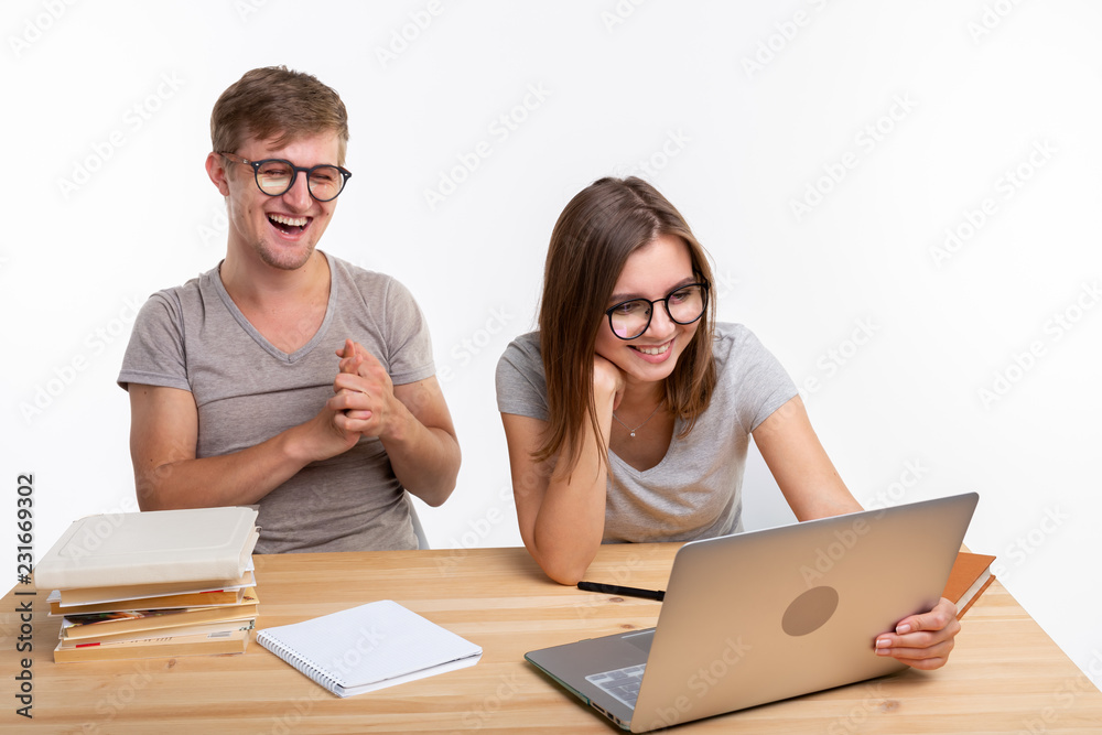 People and education concept - Two laughing students sitting at a table People and education concept - Two laughing students sitting at a table