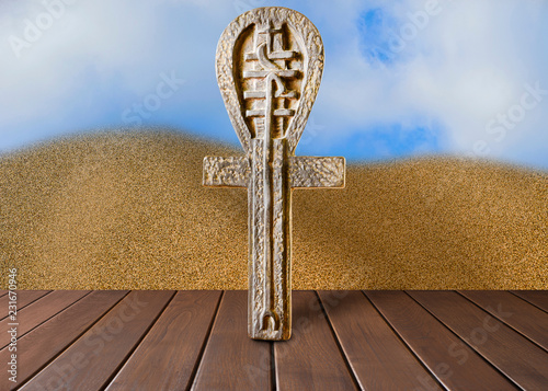 Ankh symbol. Egyptian cross on a wooden table and sand background photo