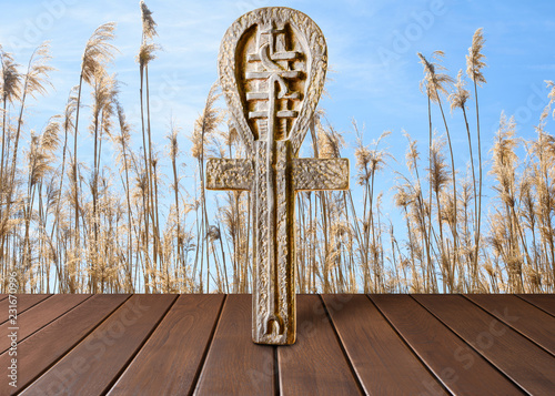 Ankh symbol. Egyptian cross on a wooden table and grass background photo