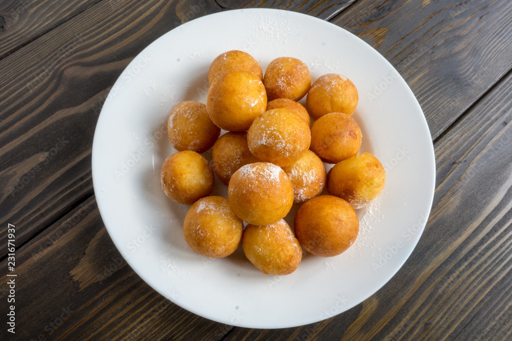 ball shape donuts, on white plate, wooden background ball shape donuts, on white plate, wooden background