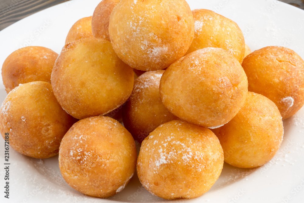 ball shape donuts, on white plate, wooden background