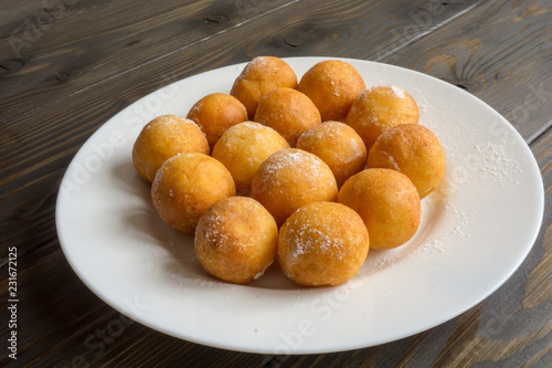 ball shape donuts, on white plate, wooden background