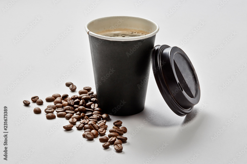 Vaso de café para llevar con tapa apoyada y granos de café
