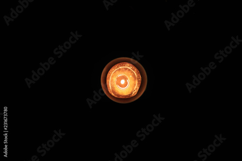 Overhead view of orange candle burning against dark black background