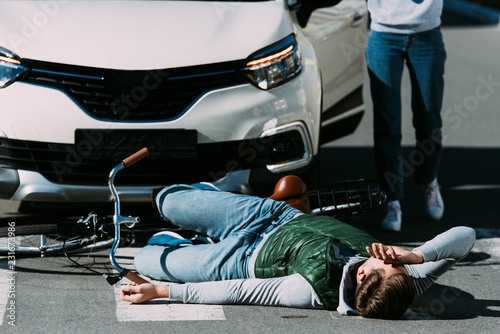 cropped shot of woman running to injured cyclist at motor vehicle collision