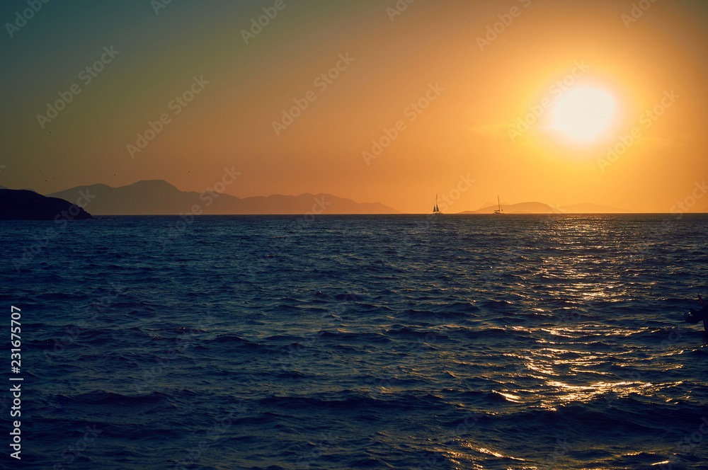 Sunset on the Turkish coast of the Aegean Sea. View of the island. Orange sky and blue sea.