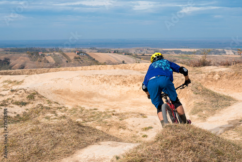 Mountain biker speeding on a mountain bike track on the top of the hill