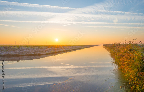 Shore of a canal in the countryside at sunrise in autumn