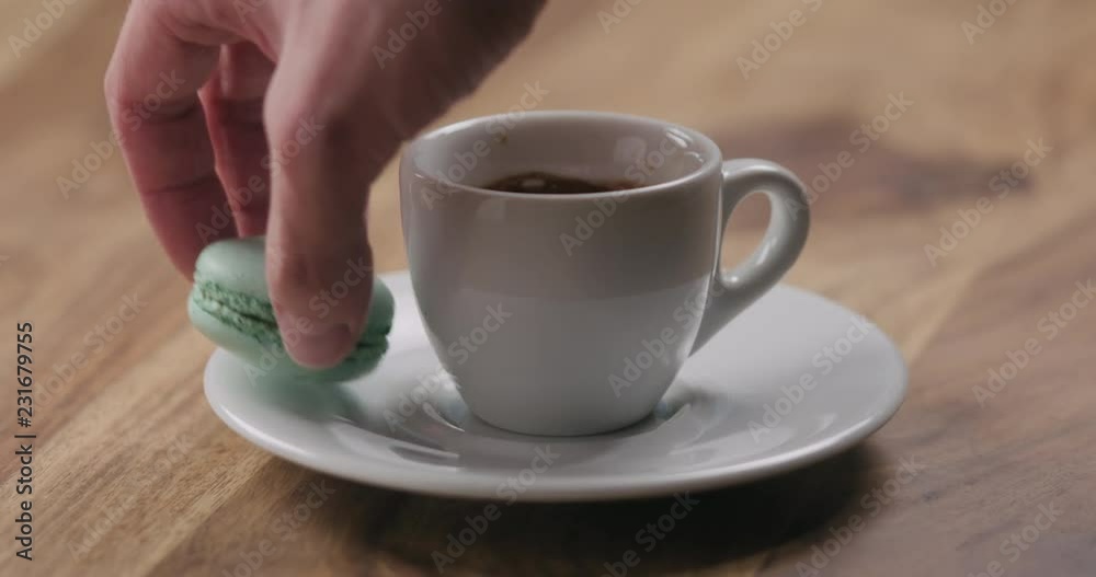 Slow motion man hand put light blue macaron on saucer with coffee cup Slow motion man hand put light blue macaron on saucer with coffee cup