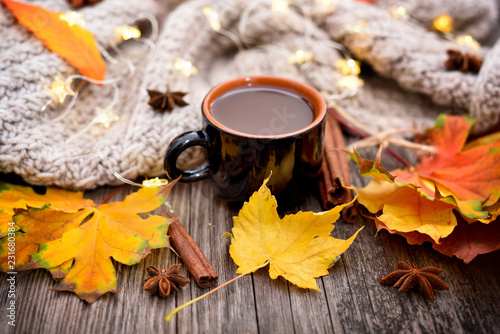 Autumn composition. Fall leaves, cup of coffee and scarf on old wooden background.