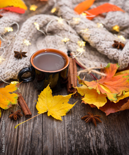 Autumn composition. Fall leaves, cup of coffee and scarf on old wooden background. © nmelnychuk
