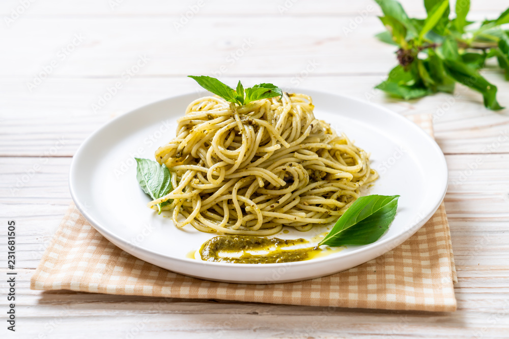 spaghetti with pesto sauce, olive oil and basil leaves.