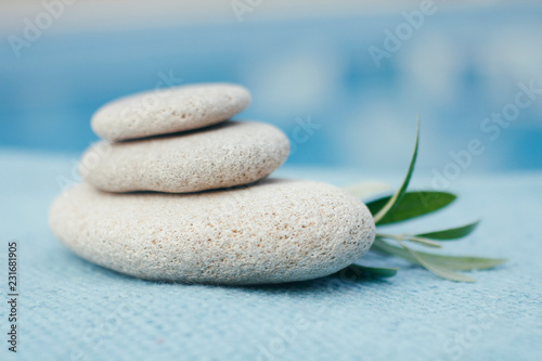 Zen stones tower. White spa stones with leaves on blurred blue background. 