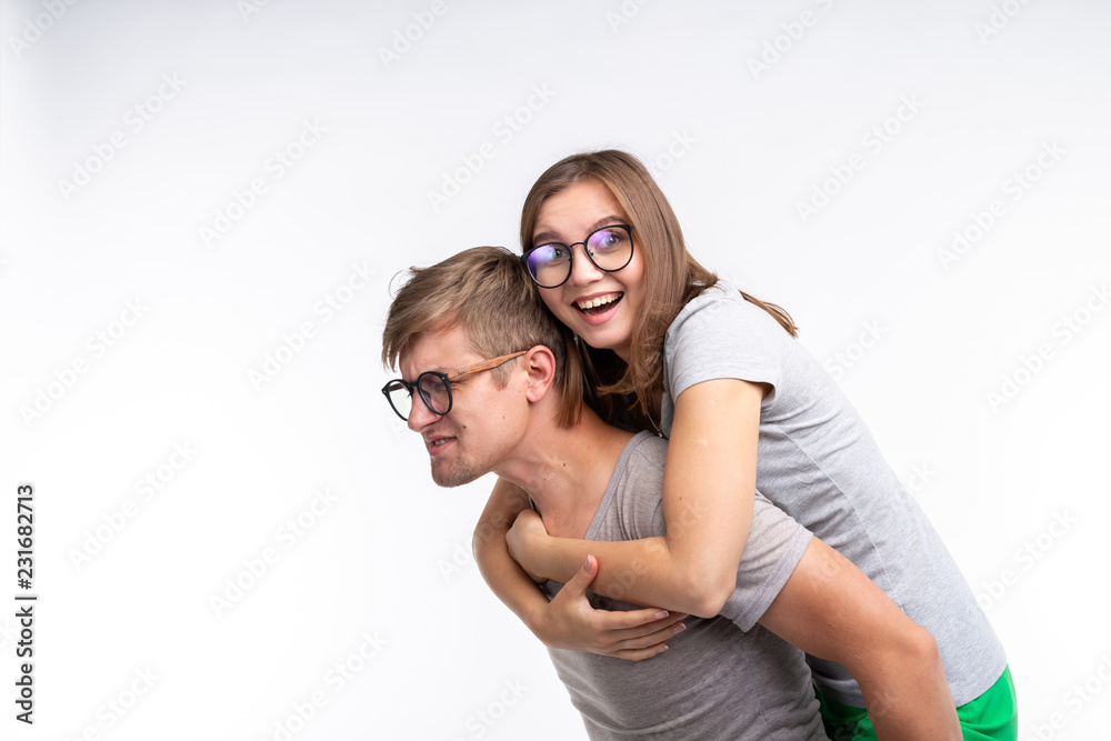 Education, funny people and joke concept - a young woman jumped on a back of man. They are happy Education, funny people and joke concept - a young woman jumped on a back of man. They are happy