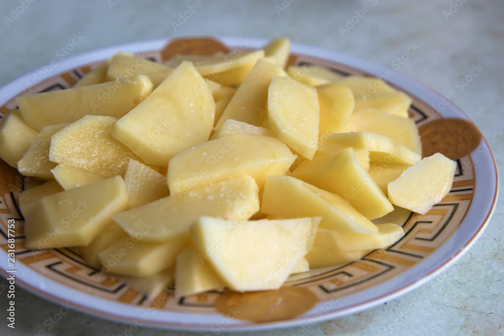 Uncooked cubical yellow potatoes on a chopping board. In the chopped potato plate . Sliced, peeled raw potatoes on a board . Uncooked cubical yellow potatoes on a chopping board. In the chopped potato plate . Sliced, peeled raw potatoes on a board .