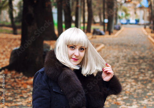 Красивая девушка с белыми волосами гуляет в осеннем парке. Белый парик.