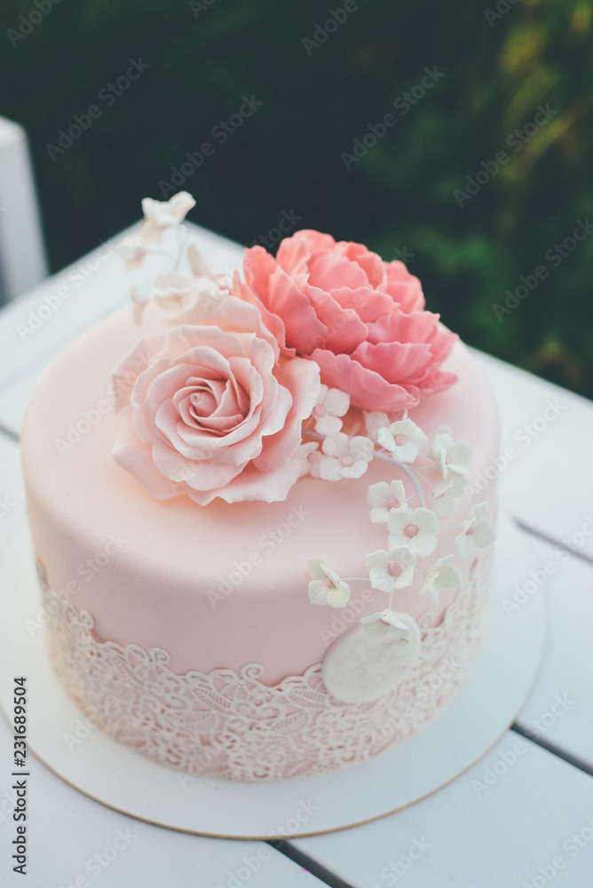 Pink wedding cake with frosting and sugar roses close up Pink wedding cake with frosting and sugar roses close up