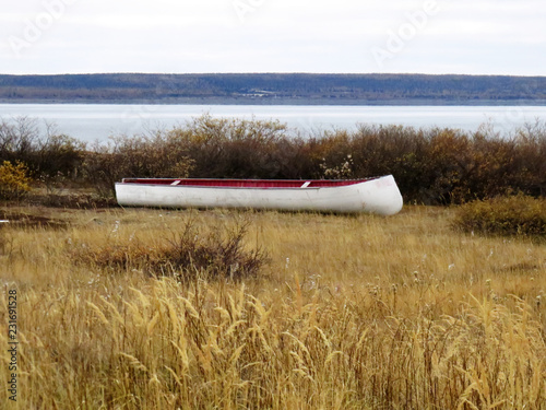 Inuit canoe resting on the grass in the fall of Kuujjuaq with water in the background