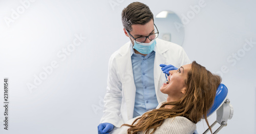 Dentist examining woman with dental equipments
