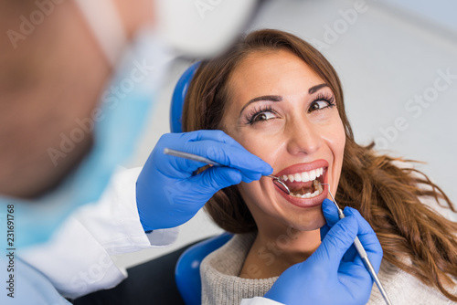 Dentist examining woman with dental equipments
