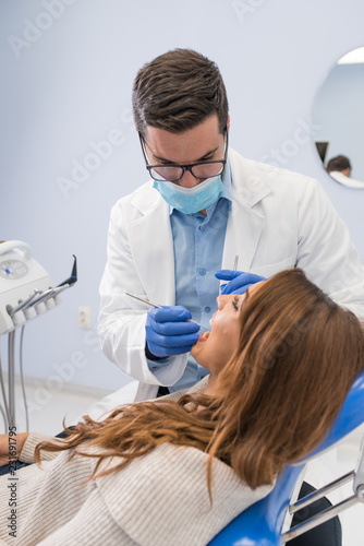 Dentist examining woman with dental equipments