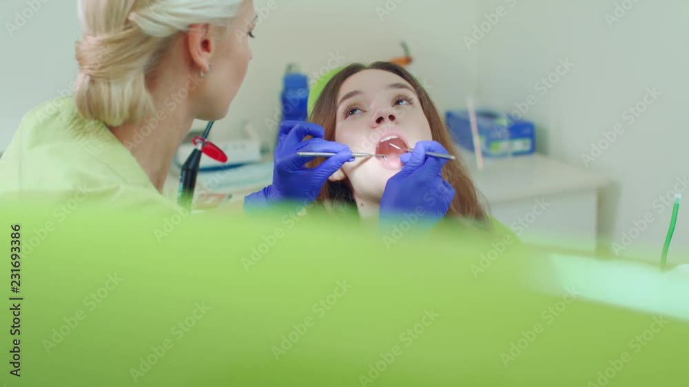 Girl having regular dental checkup. Young woman sitting in dentist chair. Female patient on dentist review in clinic. Professional stomatology specialist in dentist office Girl having regular dental checkup. Young woman sitting in dentist chair. Female patient on dentist review in clinic. Professional stomatology specialist in dentist office