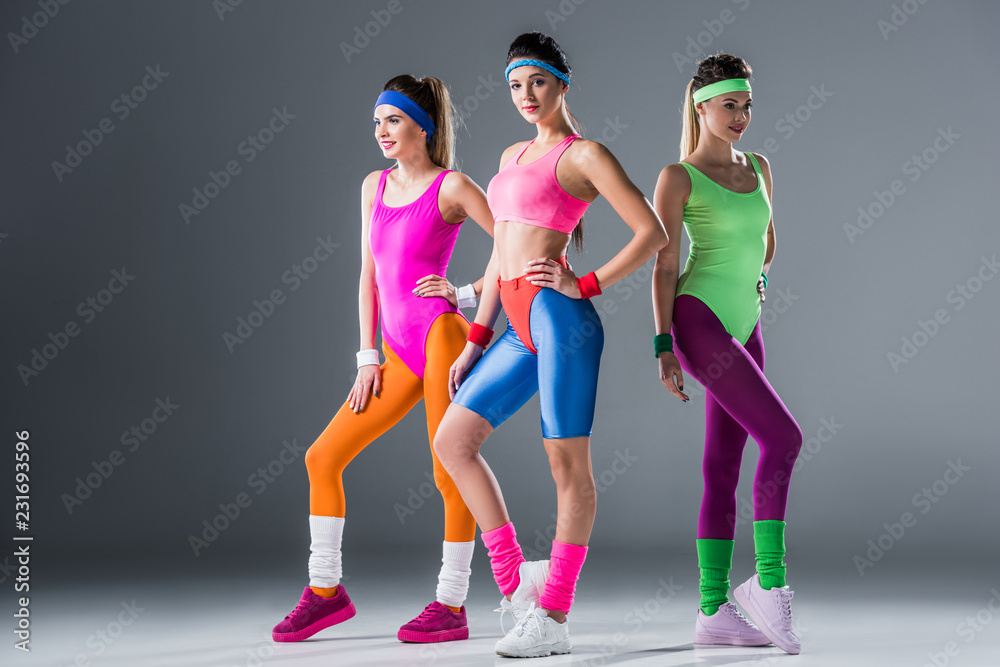 attractive sporty girls in style sportswear posing together on grey Stock-foto | Adobe Stock