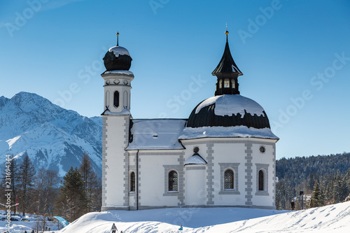 landmark Seekirchl church in Seefeld covered in snow on sunny winter day