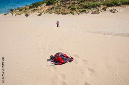 backpack on sand of beach and far woman with girl