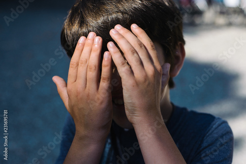 child hides his face in his hands