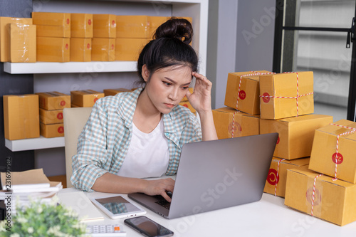 stressed woman working with laptop computer and courier parcel box at home office