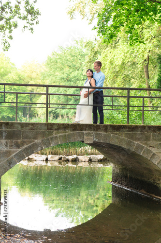 Young man and pregnant girl standing on bridge outdoor