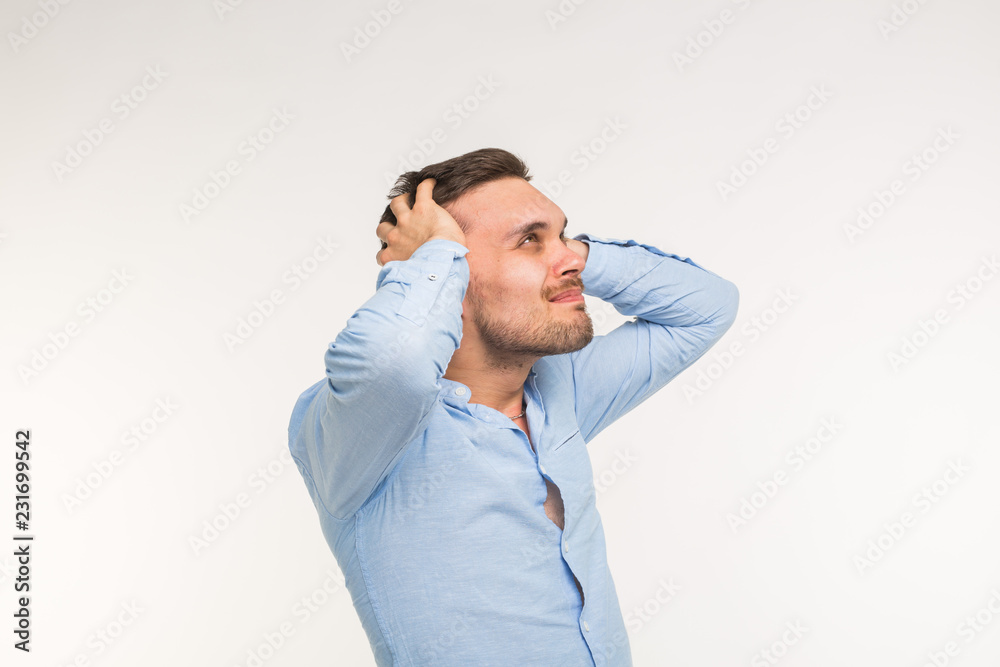 Expressions and people concept - Portrait of a young bearded man holding hands at his head isolated over white background Expressions and people concept - Portrait of a young bearded man holding hands at his head isolated over white background