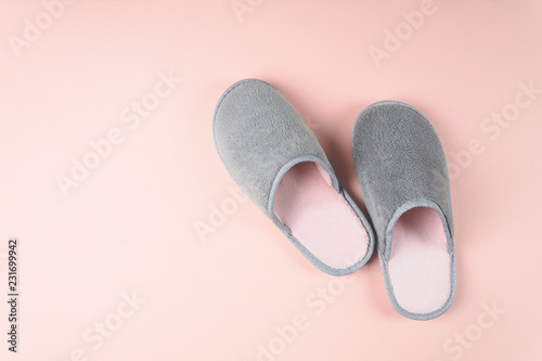 Gray and pink home slippers on a pastel paper background. Top view. Copy space. Toned
