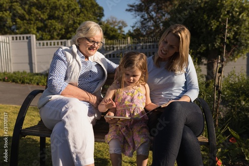 Multi-generation family looking at photo album in garden photo