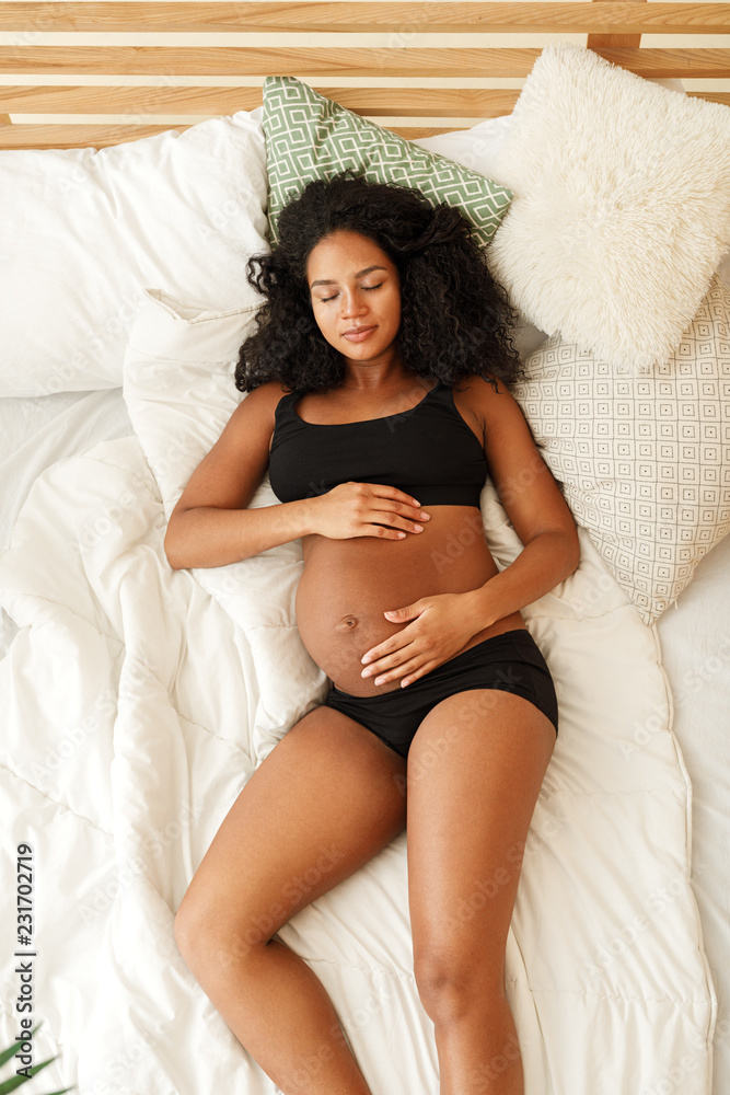 Naklejka premium High angle view of pregnant woman sleeping on the bed