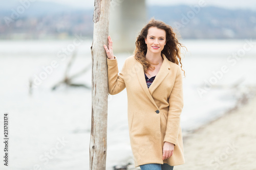 Young ginger woman  leaning on a wooden pillar at beach