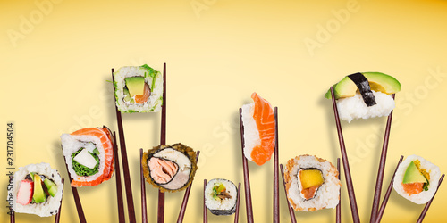 Traditional japanese sushi pieces placed between chopsticks, separated on pastel background. photo