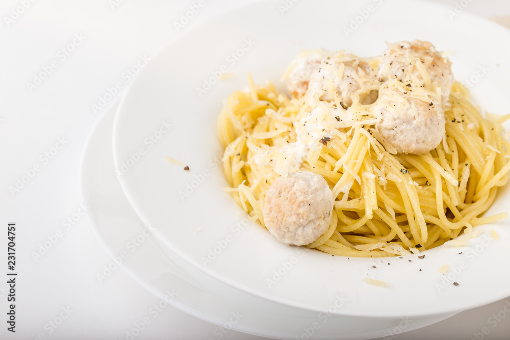Spaghetti with creamy chicken meatballs served on white plate with pine nuts Spaghetti with creamy chicken meatballs served on white plate with pine nuts
