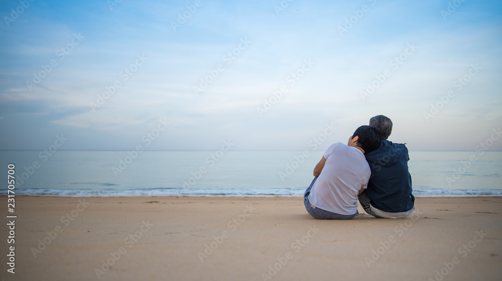 Romantic portrait of attractive couple in love hugs sitting on the beach
