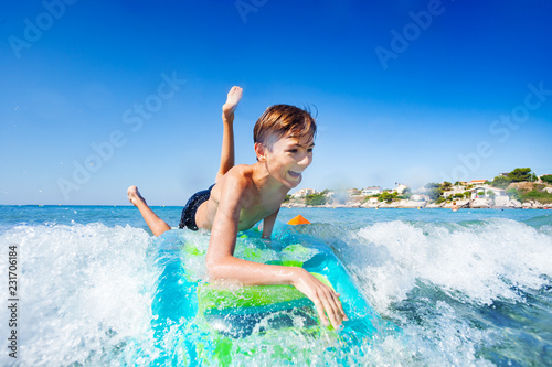 Laughing boy riding the wave on air mattress