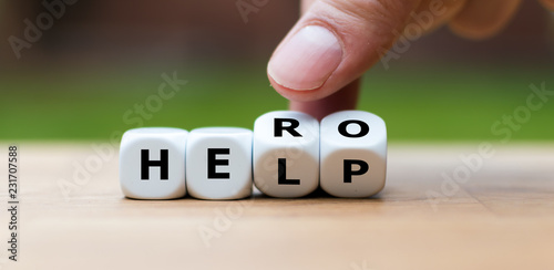 Hand is turning a dice and changes the word "help" to "hero"