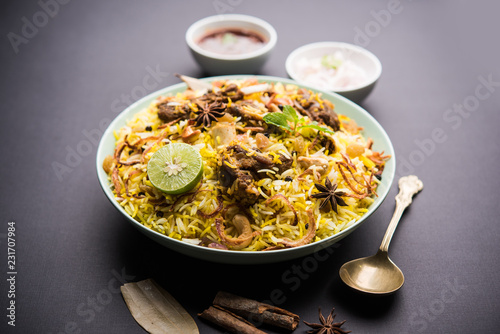 mutton or lamb biriyani with basmati rice, served in a bowl over moody background.