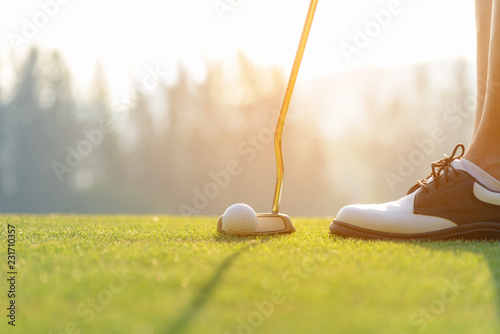 Hand asian woman putting golf ball on tee with club in golf course on evening time for healthy sport. Lifestyle Concept