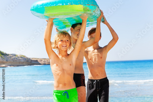 Happy boys with air mattress overhead on the beach