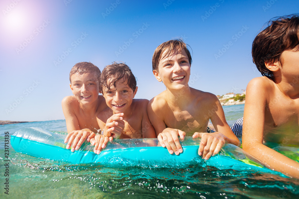 Cute boys floating together on air mattress in sea