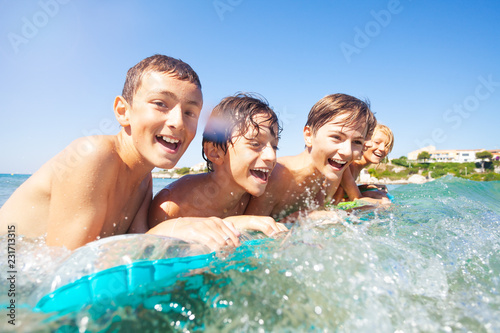 Happy boys swimming in the sea on air mattress